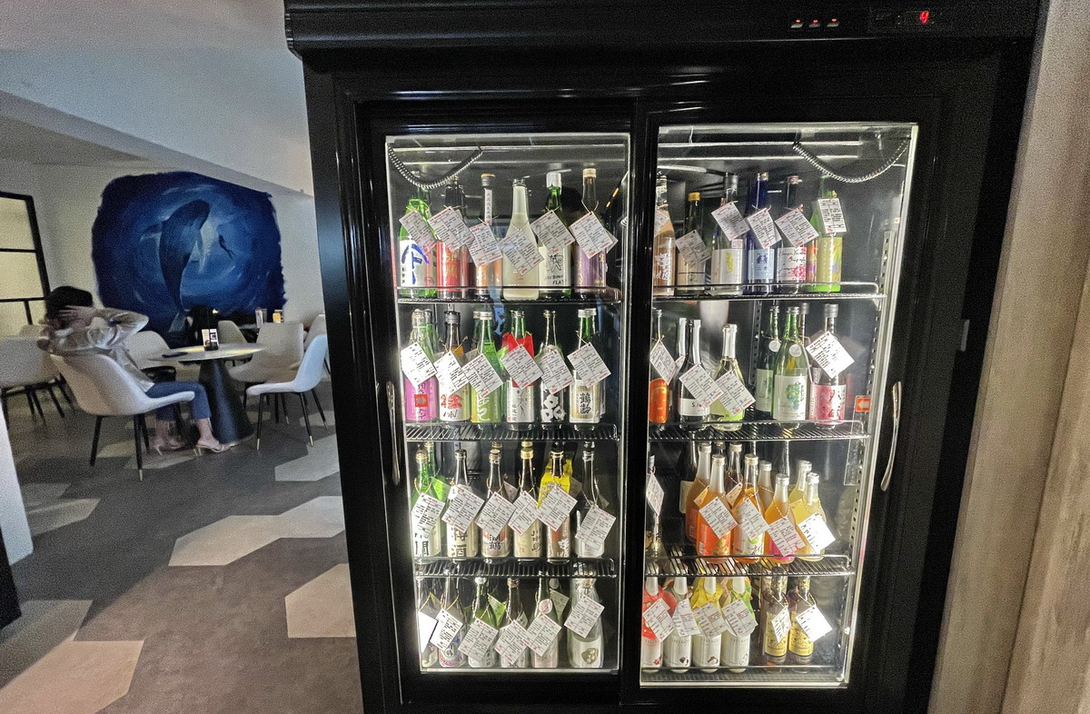 除了常溫酒，冰櫃裡也有著各式酒款。後方為海洋風座位區。酒後勿開車